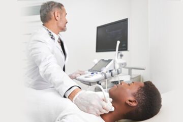 Doctor with scanning tool checking the neck of the patient while he is laying in the bed